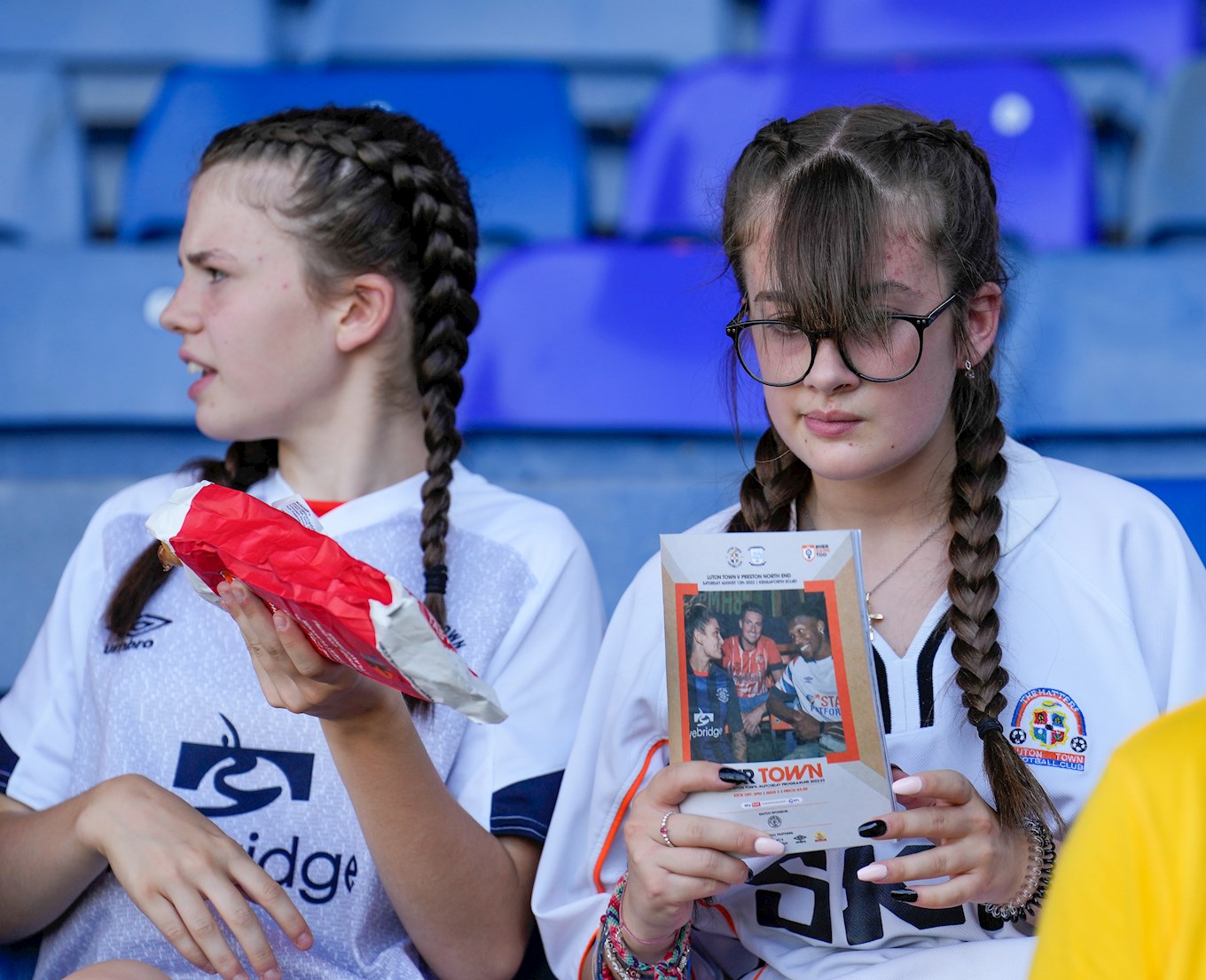 Two young female supporters read the programme ahead of the Preston match
