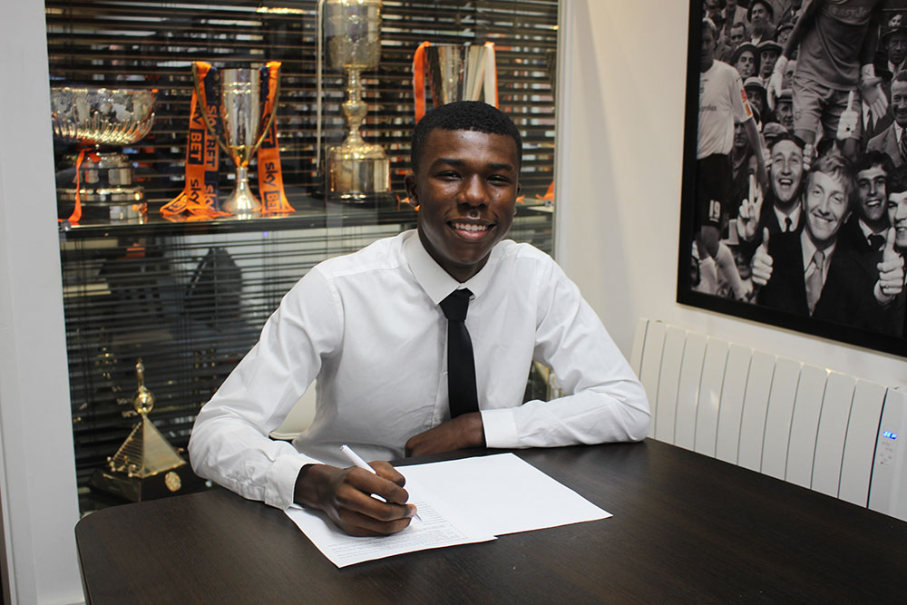 Dequane Wilson-Braithwaite signs his scholarship in the Trophy Room at Kenilworth Road