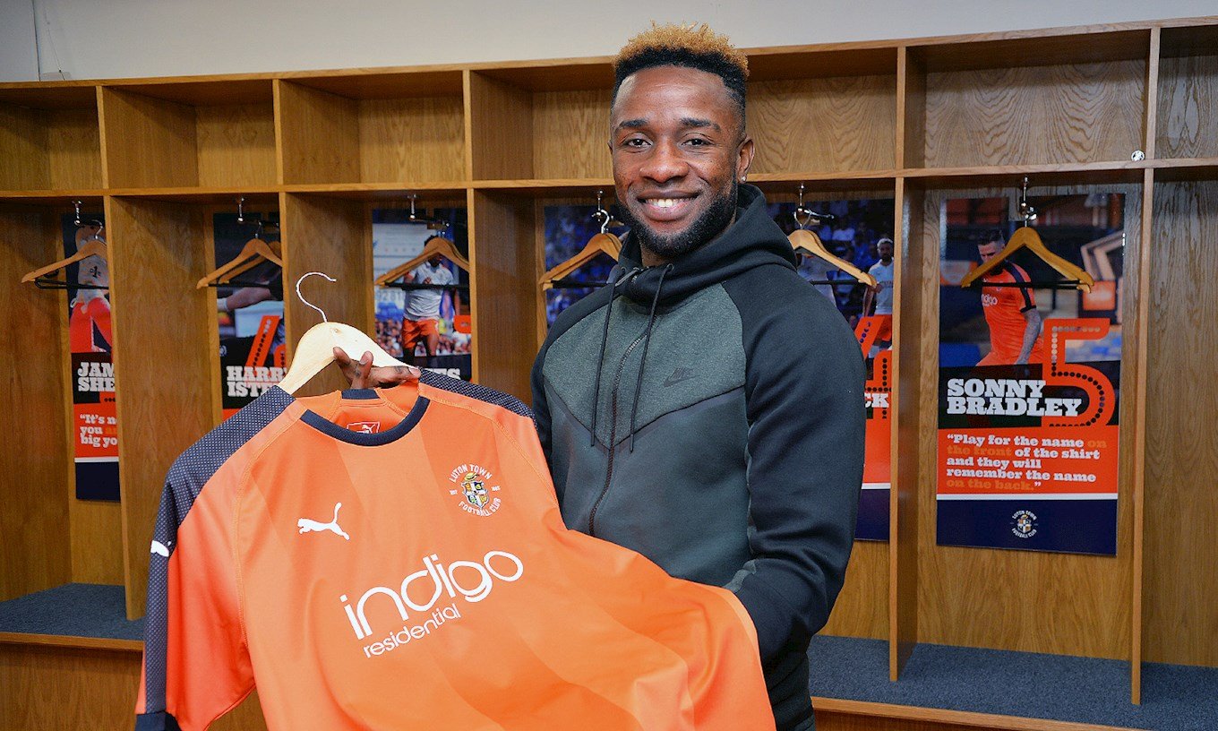 New signing Kazenga LuaLua holds the Hatters shirt in the home dressing room at Kenilworth Road