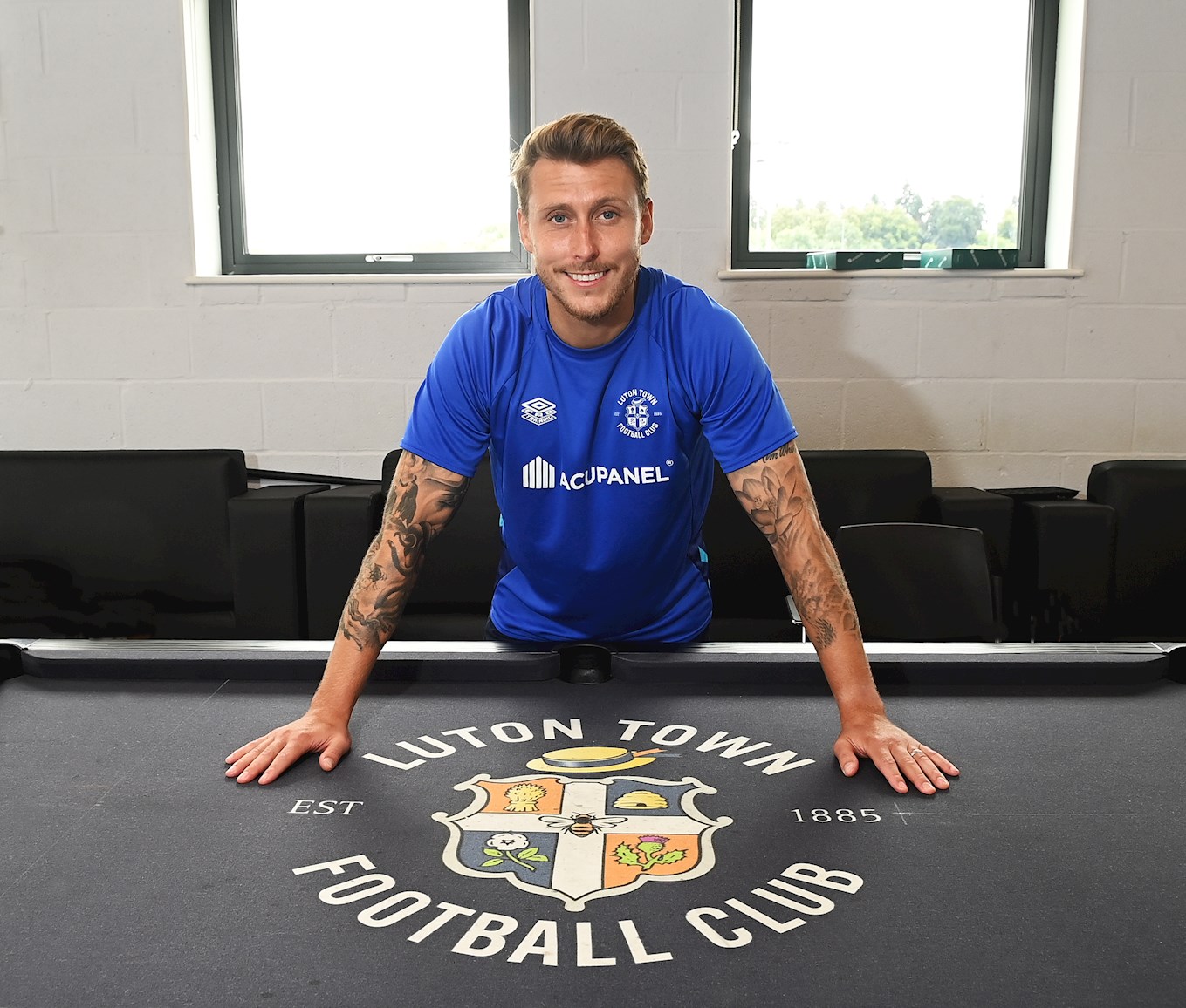 Luke Freeman poses above the Luton Town club crest on the pool table at The Brache training ground
